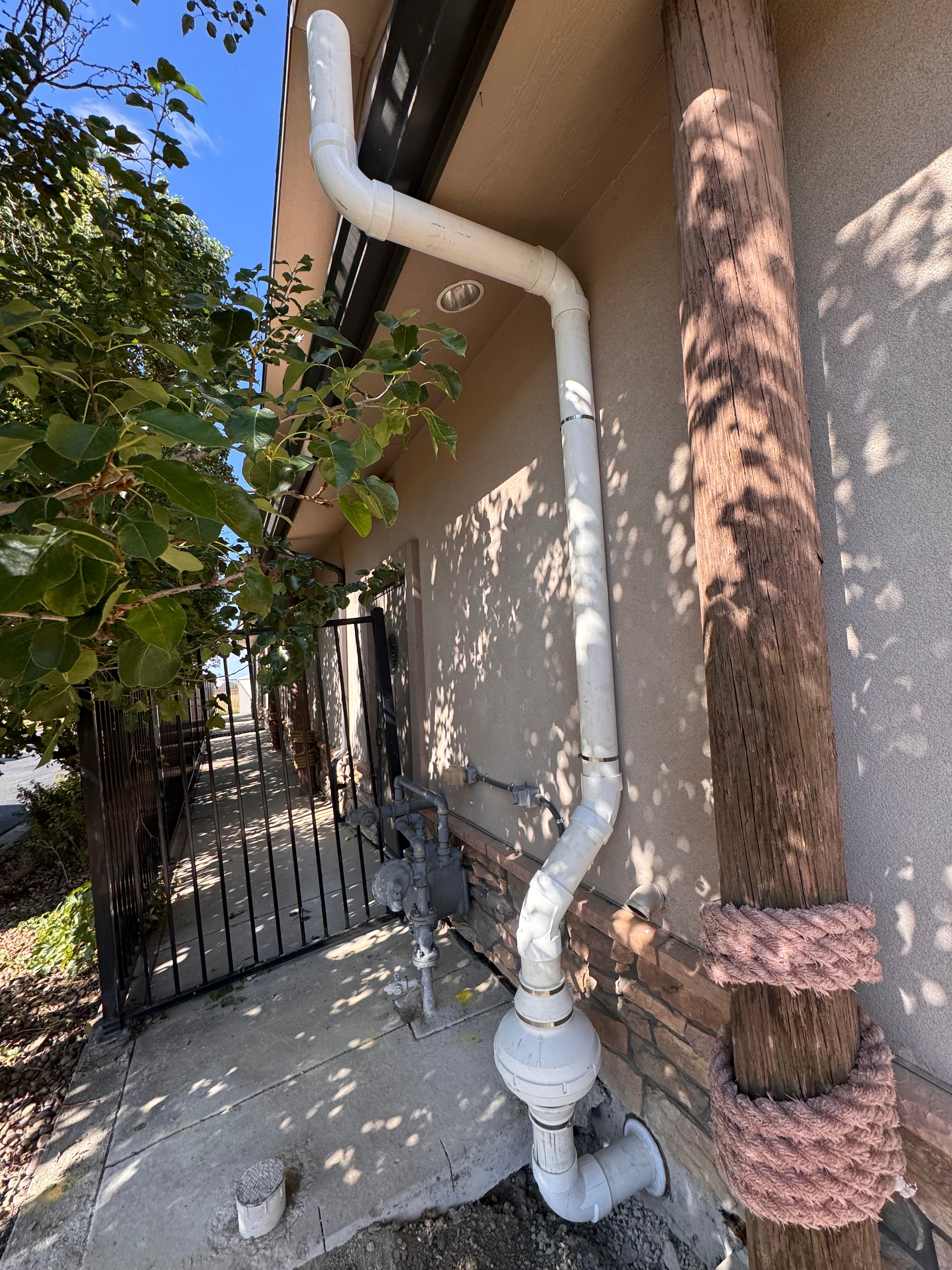 Exterior radon mitigation pipe routed down the side of a stucco Denver home
