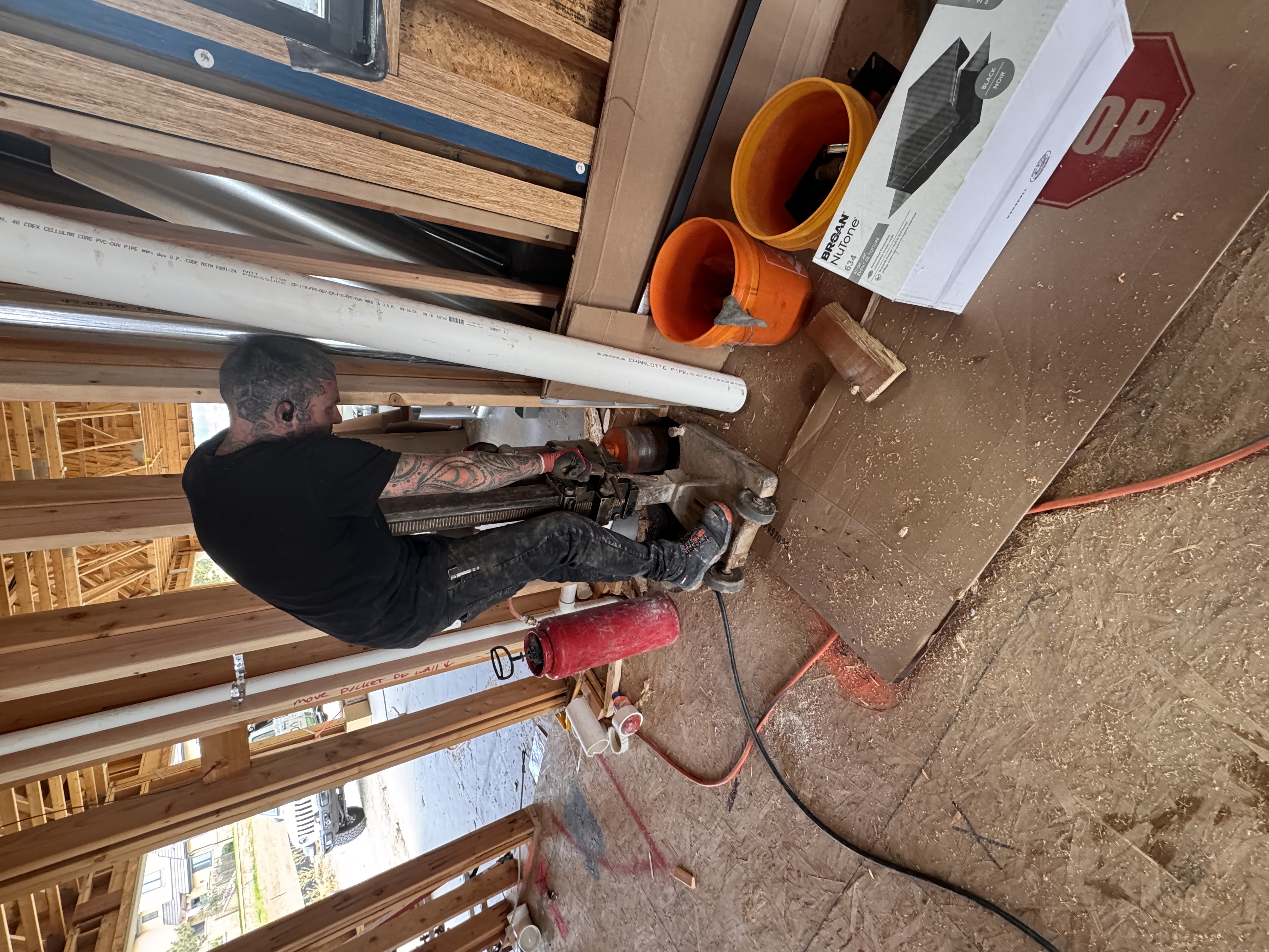 Custom Radon technician core-drilling a suction point during a residential radon install