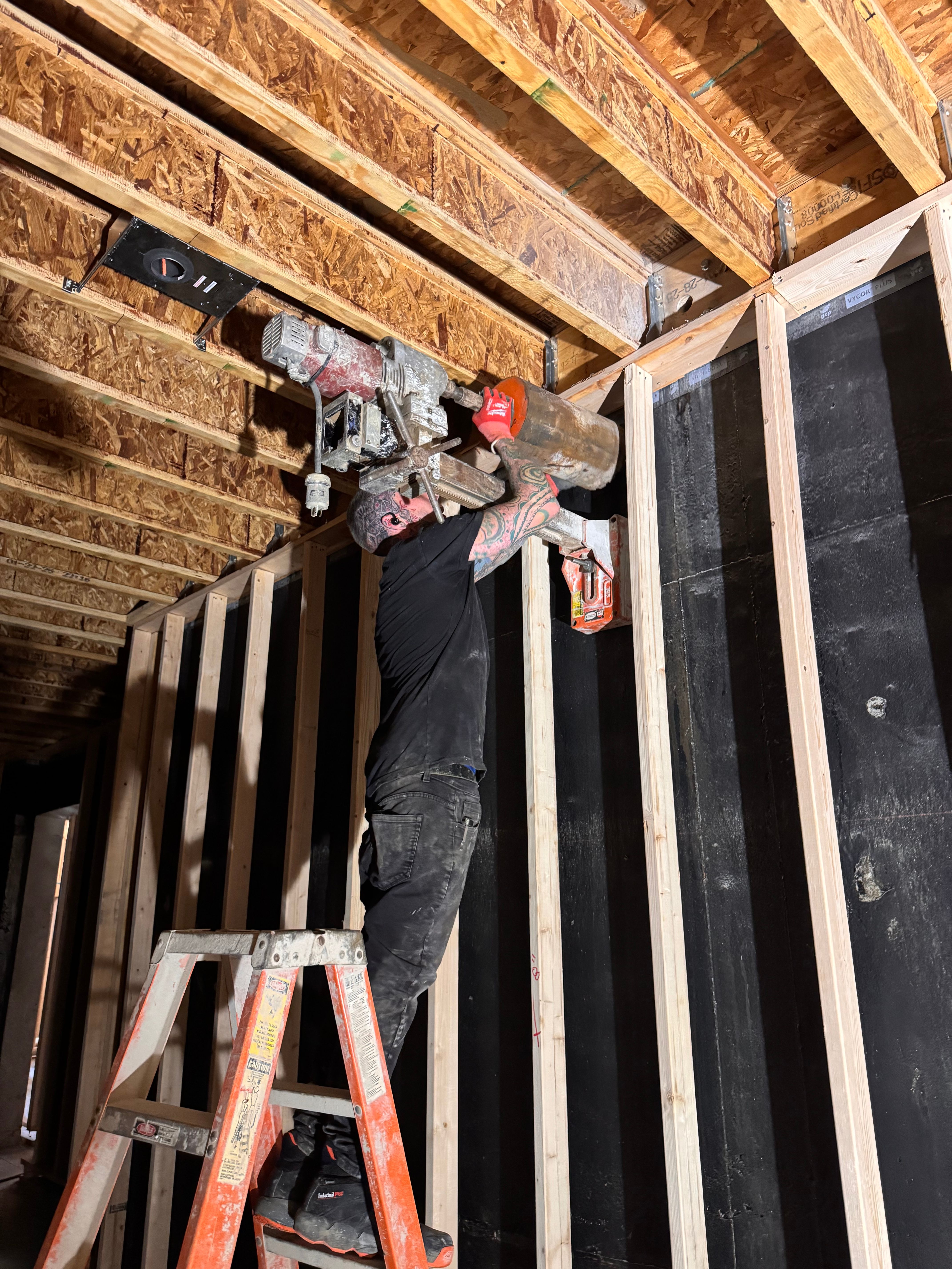 Custom Radon technician core-drilling for a radon pipe during an install
